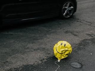 deflated smiley face balloon on the street