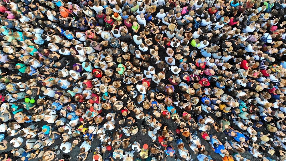 Aerial shot of people in a crowd, representing a community that is a key aspect of building CX and EX journeys. By Dmytro