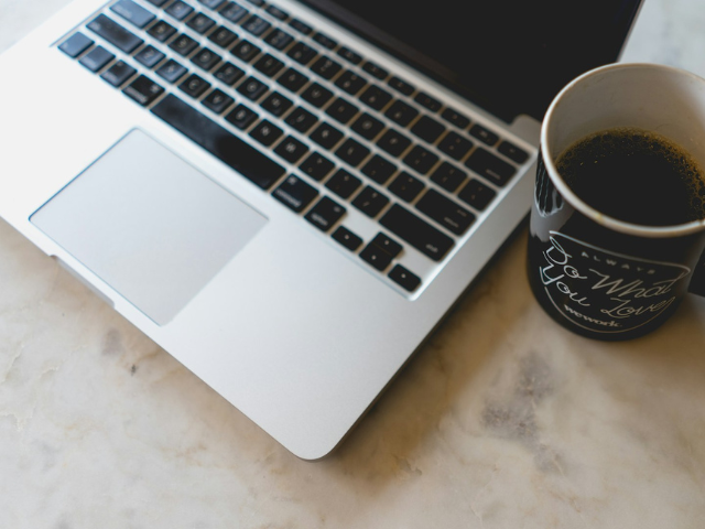 A cup of coffee next to a macbook