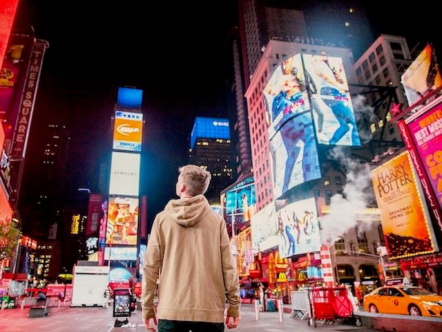 young man looking up at all the ads in Times Square