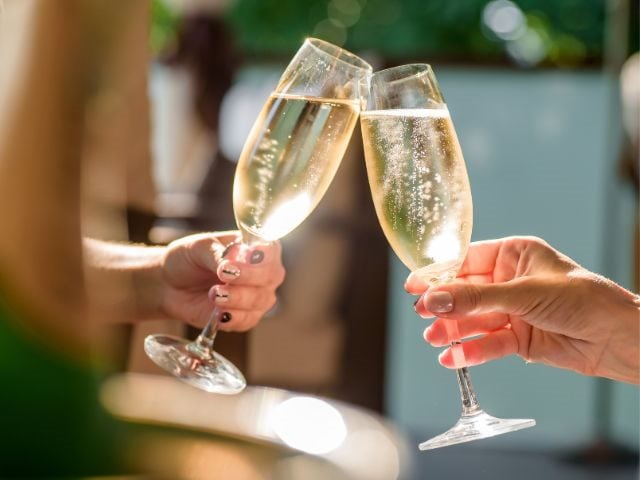 Two hands, each holding a glass of champagne 