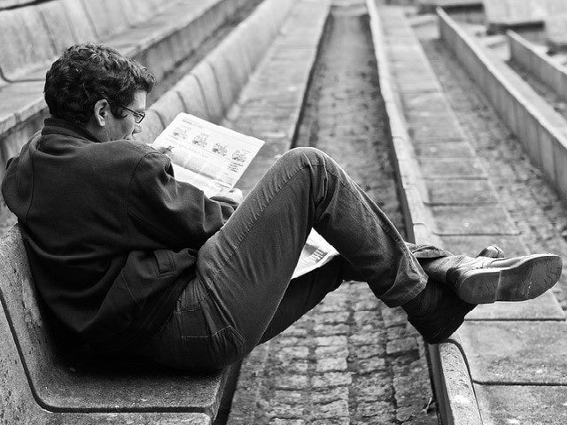 Man sitting down reading a newspapers.