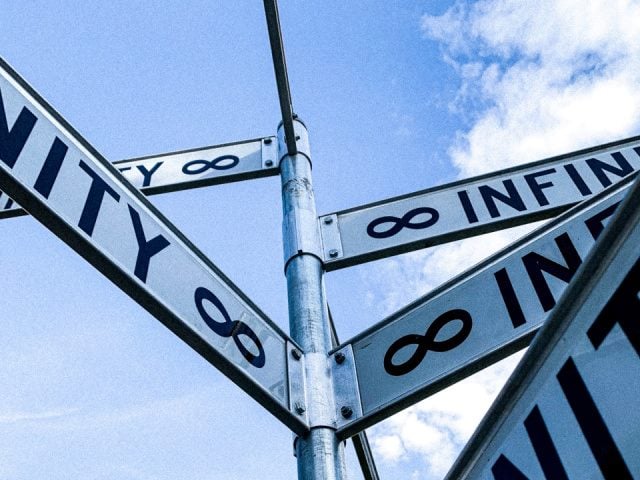 Infinity street signs against a blue sky