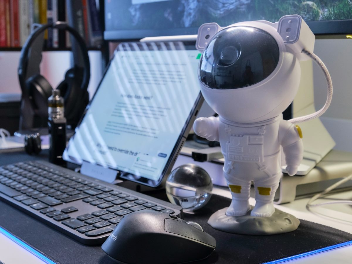 A small robot toy standing next to a laptop.