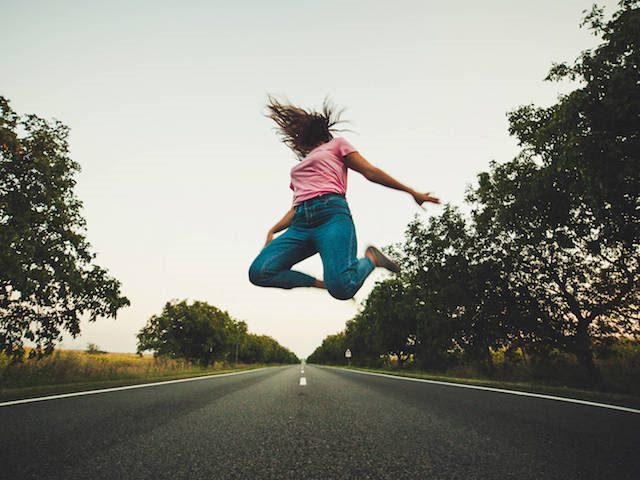 woman leaping in middle of the road