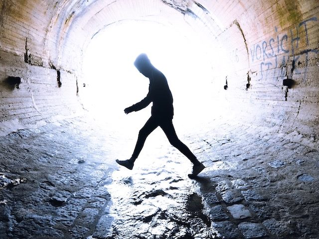 person walking through a tunnel with water flowing through it