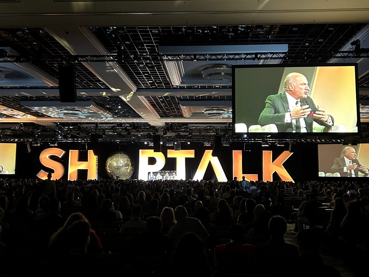 Scene from a keynote at Shoptalk in Las Vegas with Kevin O'Leary on a large digital screen.