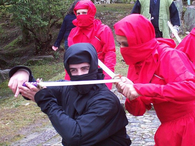 People dressed up like ninjas holding swords.