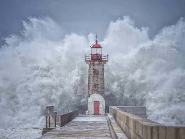 A big wave crashing over a secure lighthouse - security lookout concept