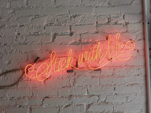 neon sign reading "stick with me"