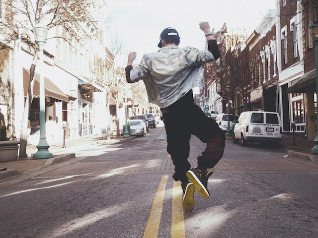 man jumping up and clicking his heels in middle of street