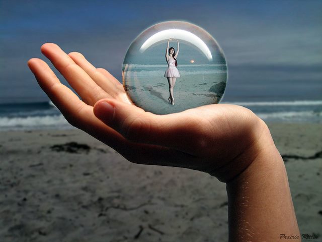 Person holding a globe of a tiny dancer