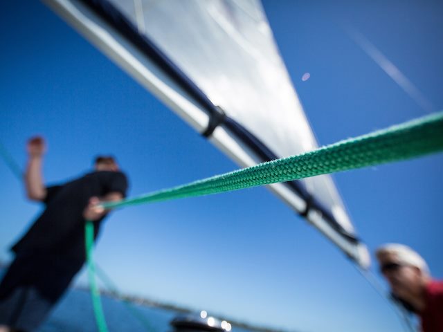 out of focus shot of a man tying a rope to a sail