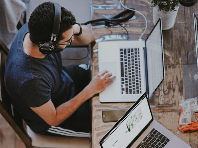 man with headphones on looking at a laptop