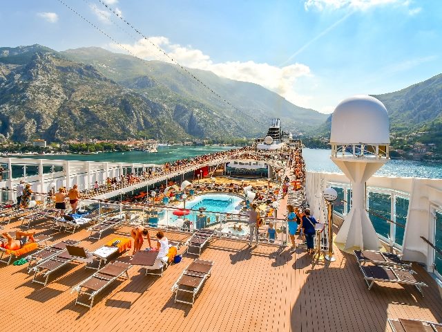 Tourists on a large cruise ship on Boka Bay near Perast heading towards the Kotor Montenegro cruise port on the Adriatic Sea. Cruises need to offer great EX and CX.