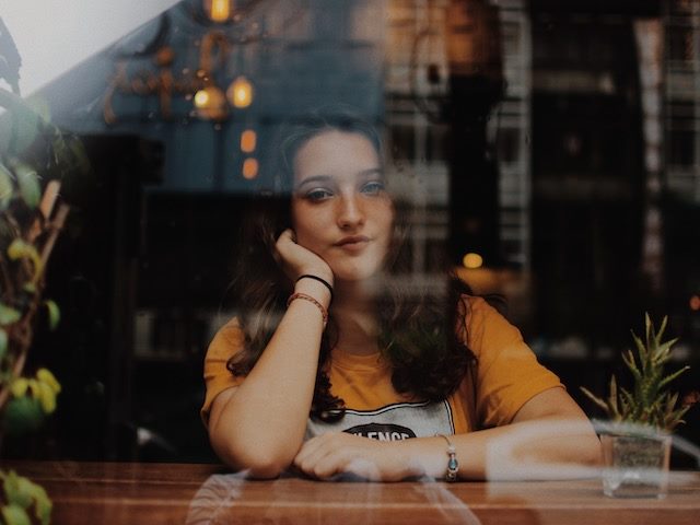 woman looking out the window of a cafe