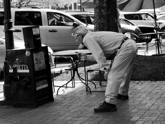 A man looks into a newspaper box.