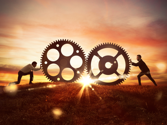 Two businessman integrating giant gears on a hilltop, making them turn. - AI and Collaboration in the workplace concept