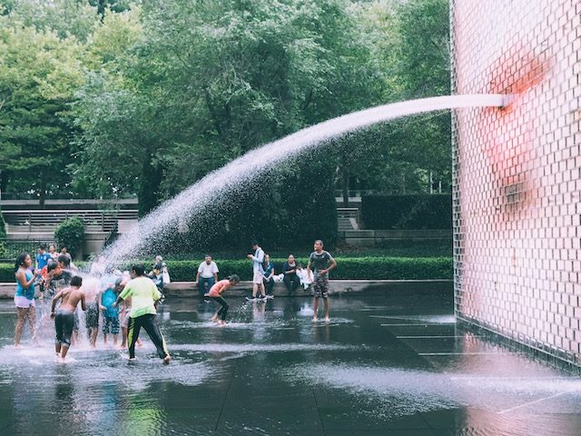 sculpture in Chicago's millennium park, video of a human face with a hose of water coming out of the mouth, kids playing in stream