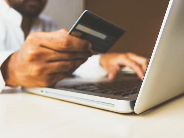 person with a credit card  in hand, about to complete an online ecommerce transaction