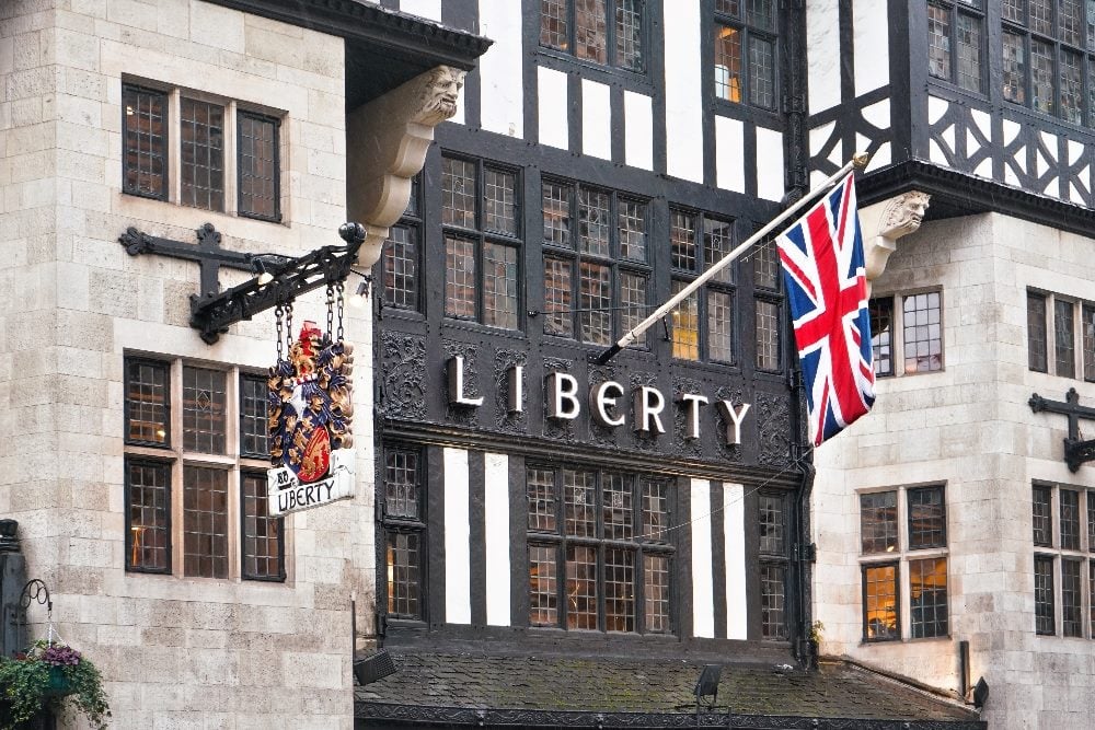 The facade of Liberty London department store with name on the front o the building and United Kingdom flag, a case study in how the store uses AI to improve customer experience.