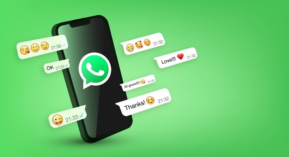 Whatsapp green and white telephone icon in a speech bubble on a smartphone screen, with chats and emoticons visible to the sides .