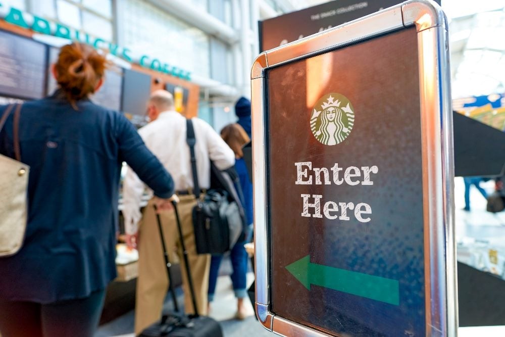 Starbucks Cafe at O'Hare Airport in Chicago with an "Enter Here" sign with the Starbucks name and logo on it on the right and customers in a line on the left in piece about customer experience strategies and good friction.