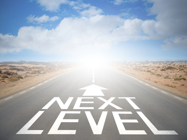 A road in the desert that goes of to the horizon. On the road is an arrow and the words next level 