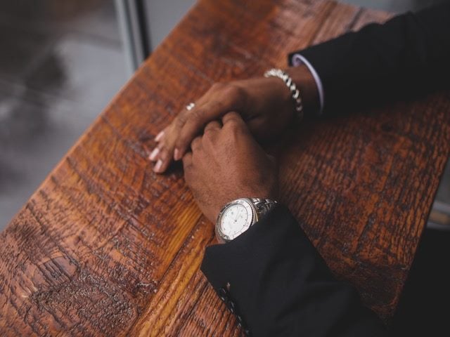 person with hands folded on a table