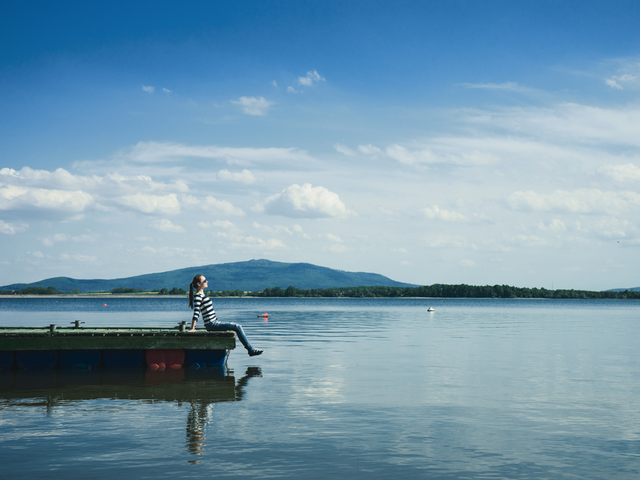 Woman sitting on a wooden jetty enjoying the sunshine