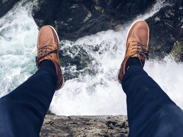 man standing on a ledge over a deep ravine