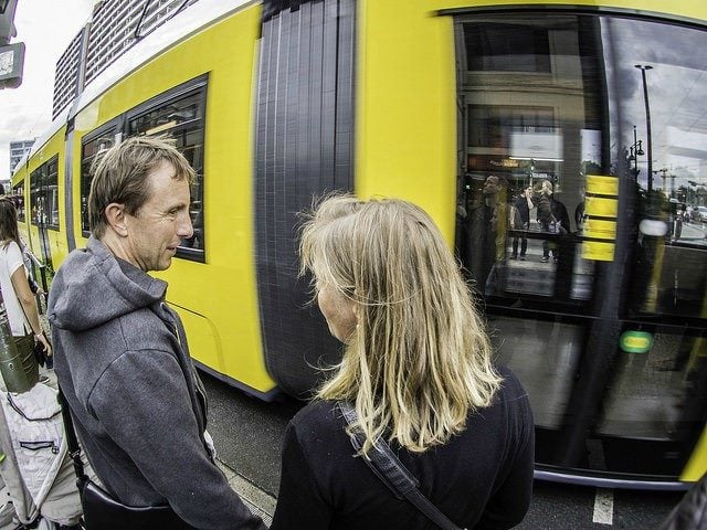 A man and a woman talking while waiting for the tram.