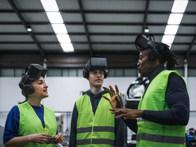 Team of three engineers having simulation experience with futuristic virtual reality glasses.