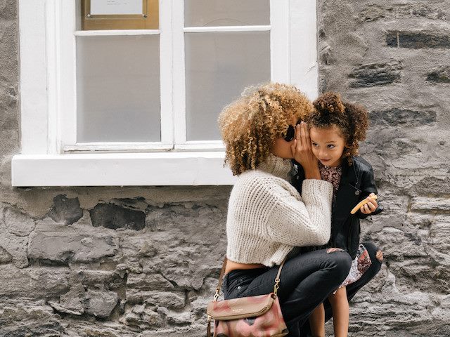 woman whispering in a child's ear