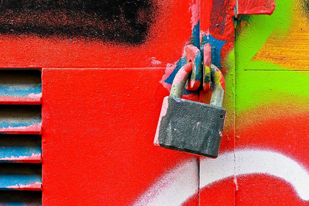 An image of a padlock on a brightly colored wall with red, green, and blue graffiti. The padlock symbolizes security and protection, reflecting the concept of data privacy.