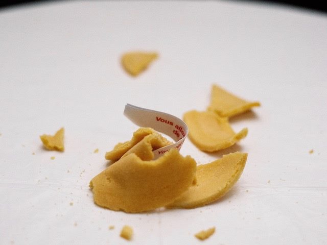 fortune cookie, broken on a table, fortune sticking out
