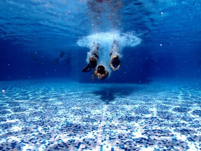 swimmers diving into a pool