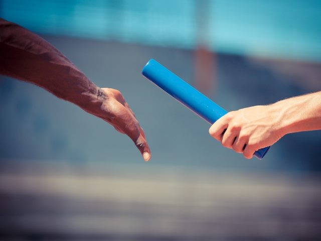 Passing the relay baton, showing two hands. 