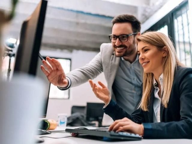 Two office workers debating analytics data on a screen in front of them
