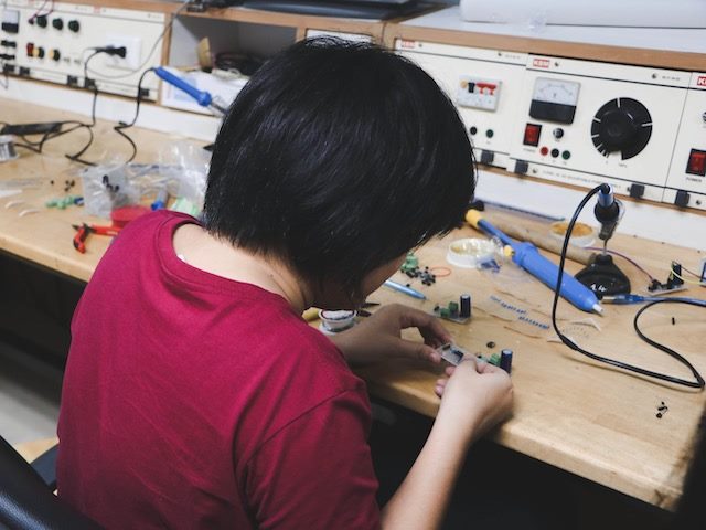 woman sitting at a table working on circuits