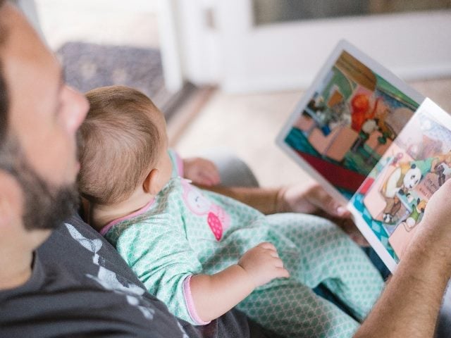 A man reading a book to a baby.
