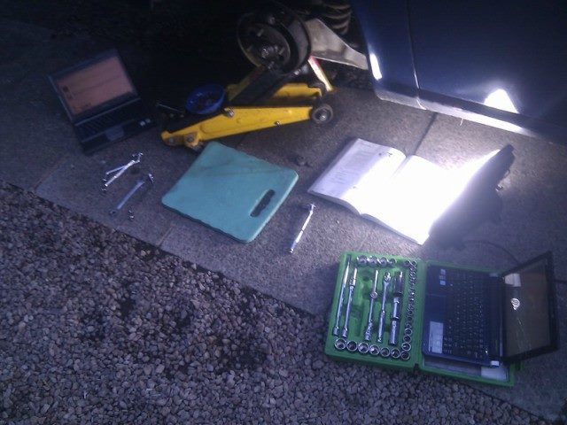 a light shines on a laptop, a laptop cover and other various tools.
