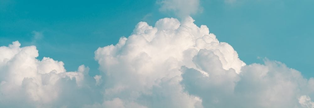 A panorama of white clouds and a vibrant blue sky in the background in a piece about cloud migrations.