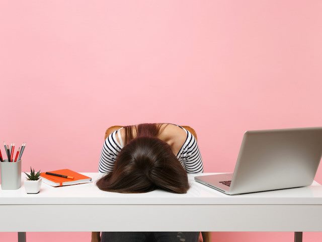 woman with head down on desk in frustration