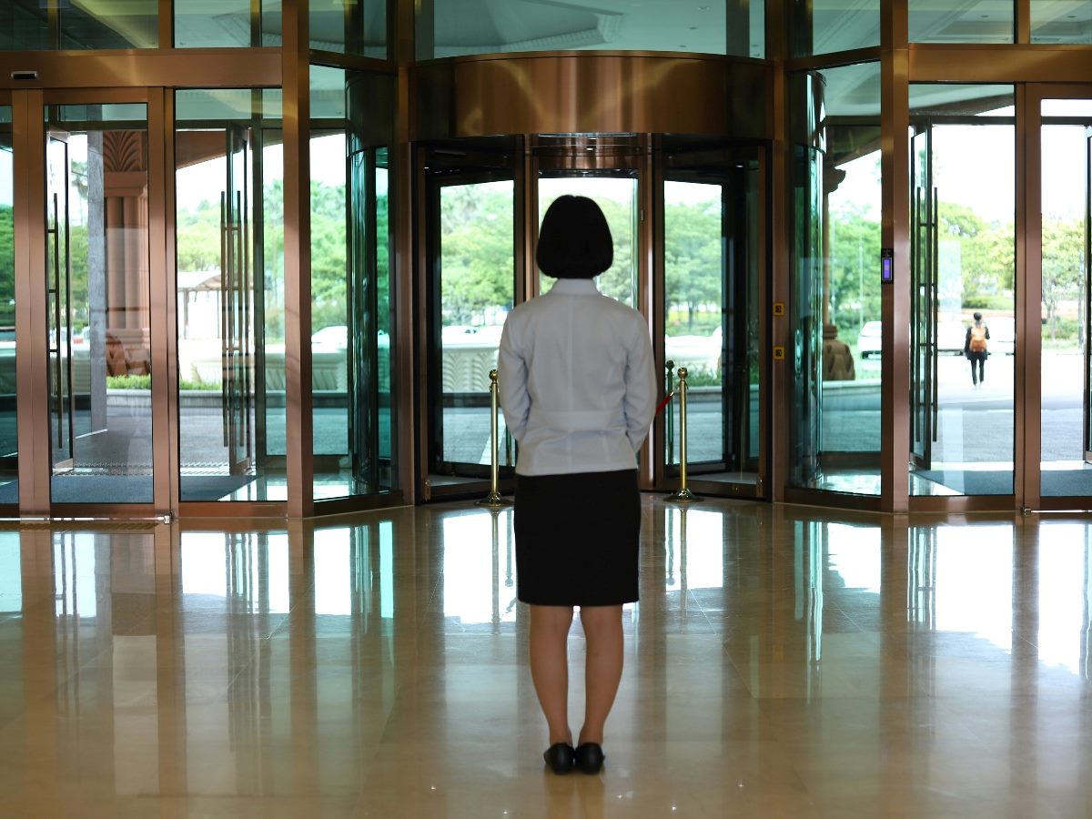 Woman standing and looking at a revolving door ahead.