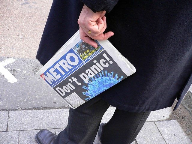 A business man holding a newspaper with the headline, "Don't panic." Photo only shows lower half of the man.