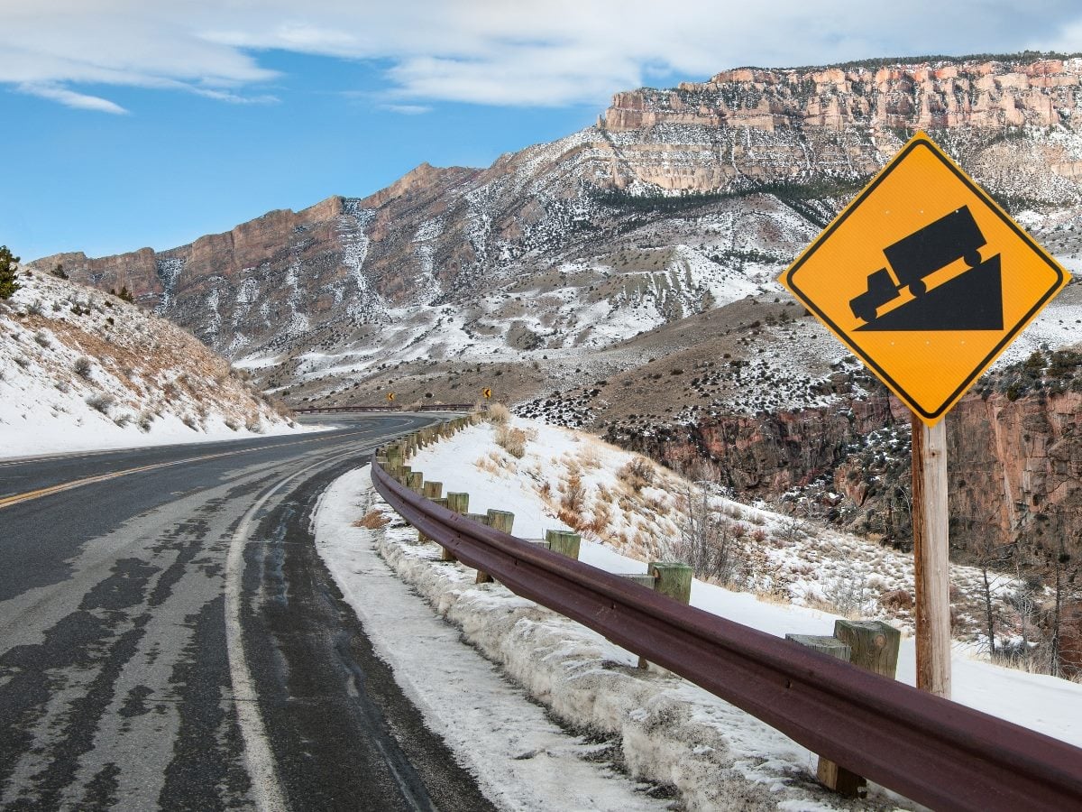 Steep Grade Warning Sign: Drivers are warned of a steep downhill drive ahead on a mountain road in Bighorn National Forest. 