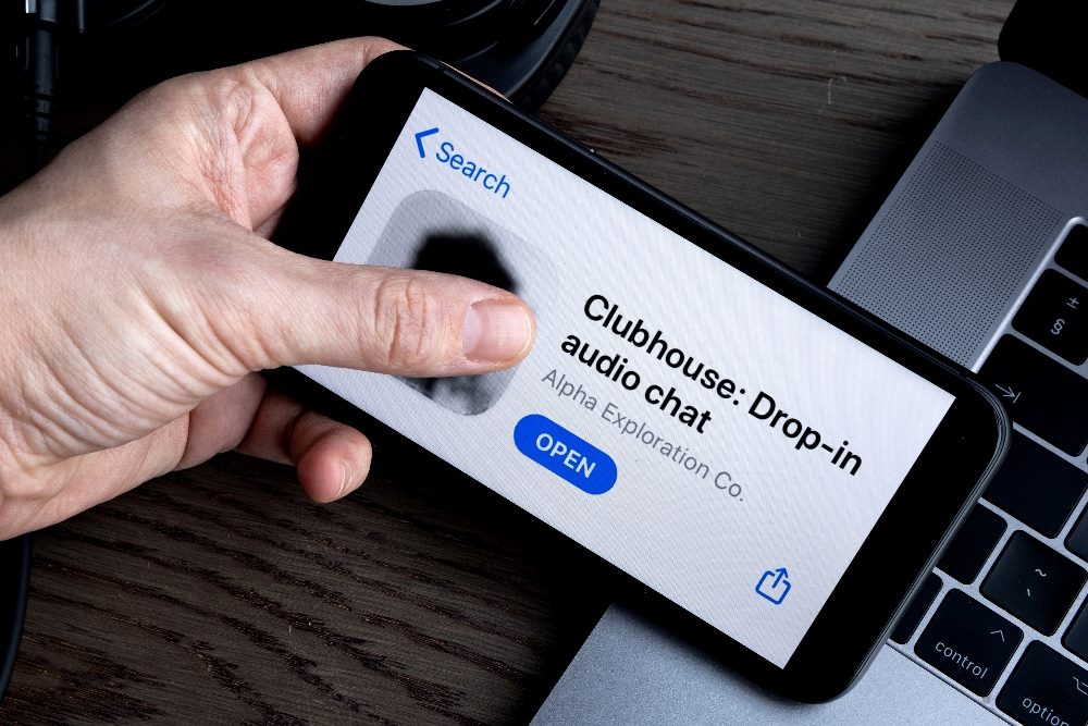 A man holds a smart phone with Clubhouse name and logo showing in piece about social media rebranding.
