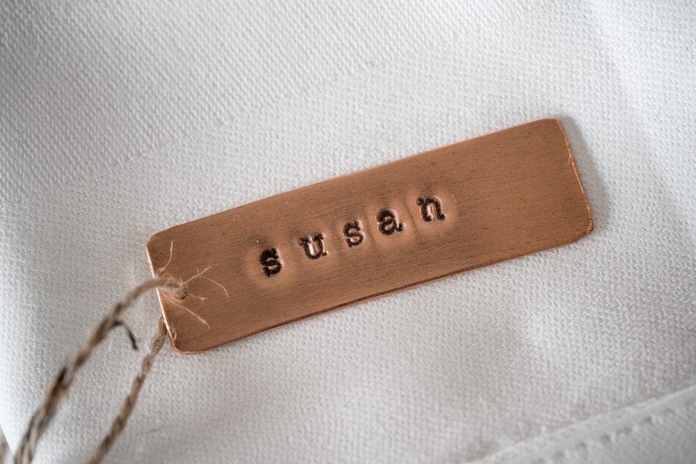 A "brass dog tag" necklace is stamped with the name "Susan" on a white cloth background in piece suggesting the need for a personalization strategy.
