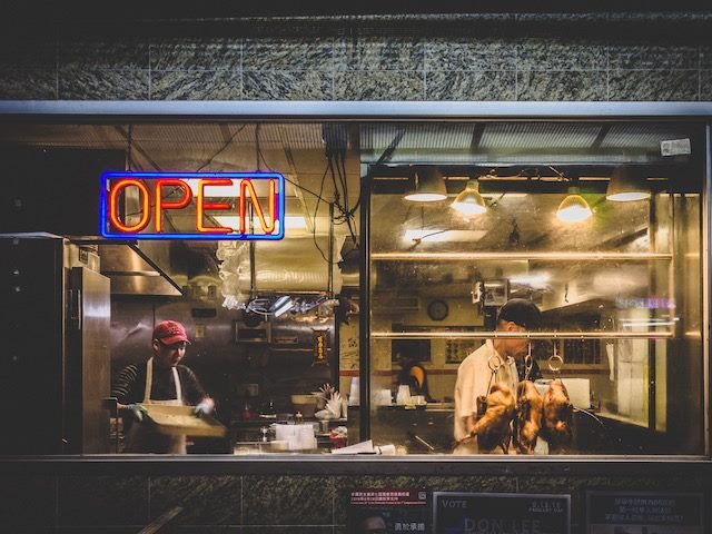 Chinese restaurant at night, ducks hanging in the window, open sign lit up